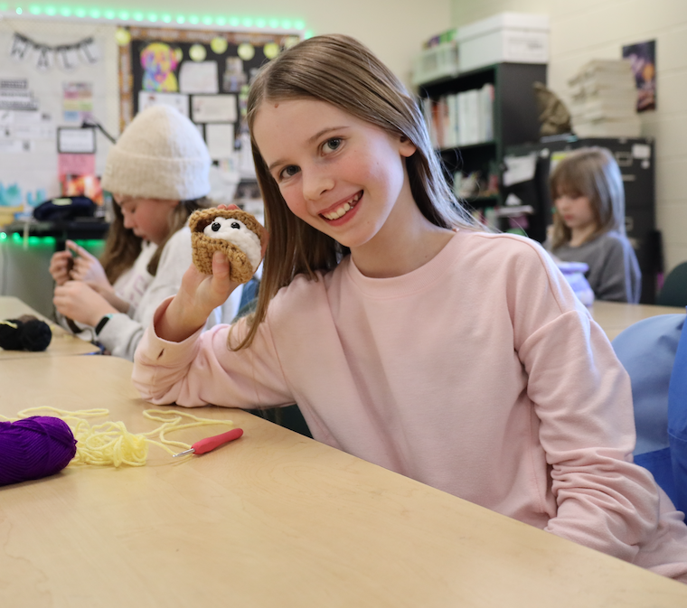 student with crochet creation