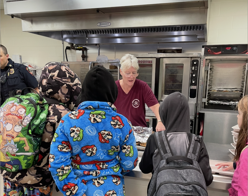 Nutrition Services staff member serving breakfast to students