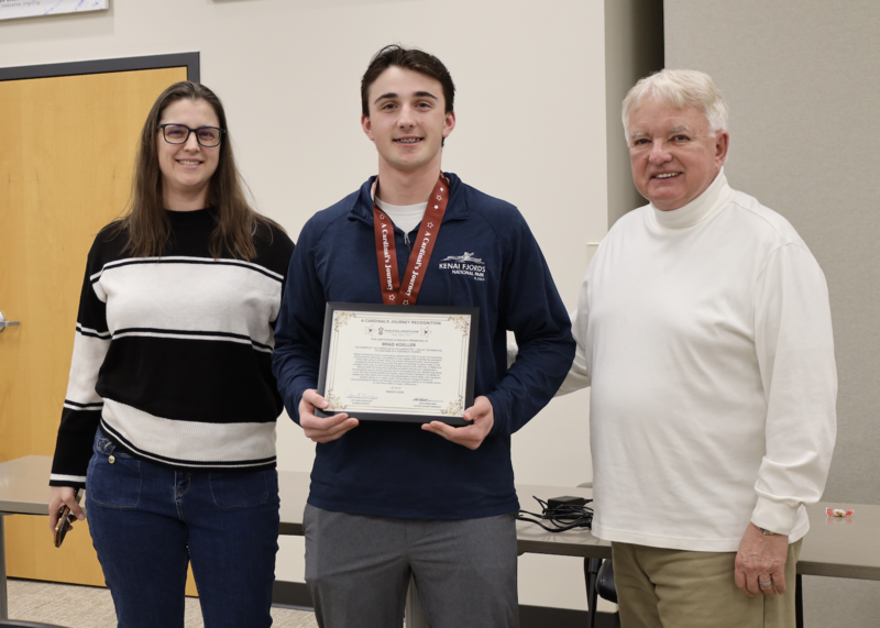 Bri Carroll and Bob Hesselbein pose with Brad Koeller while he holds his Cardinal's Journey Award