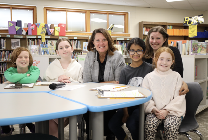 Dr. Dana Monogue and Betsy Wermuth smiling with students in the library