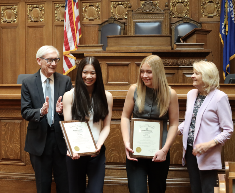 Sophia Chen and Sophia Pientka smiling in the Wisconsin Capitol Building with Gov. Tony Evers and First Lady Kathy Evers