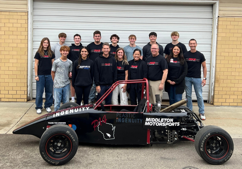 Members of the MHS Racing Team smiling with MHS and MCPASD staff in front of one of their cars