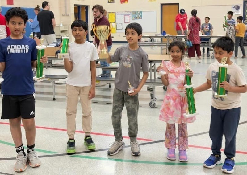 Elementary school students holding trophies after winning the school chess championship