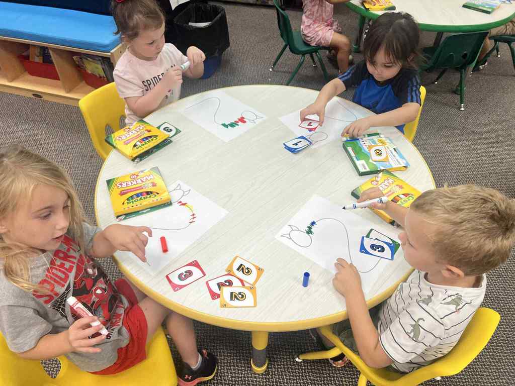 4 kuds coloring their monsters based on the uno cards.