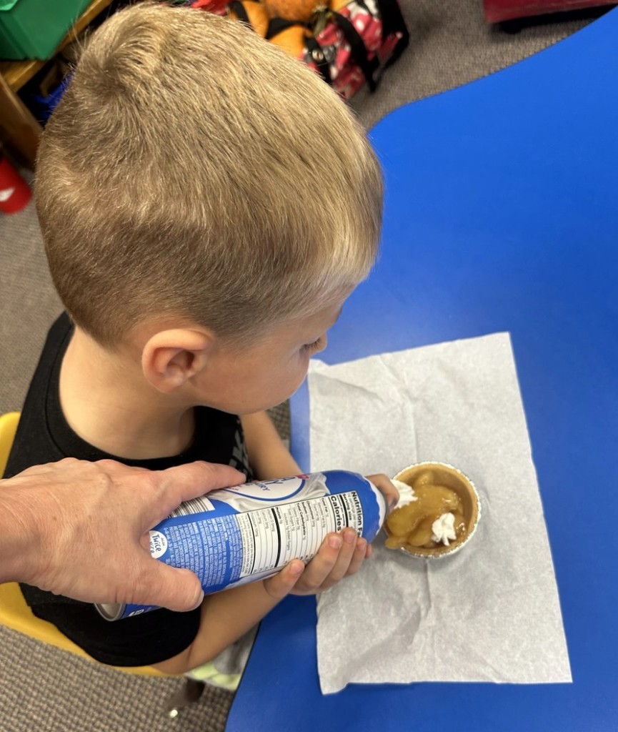 a boy putting whipped cream on a pie