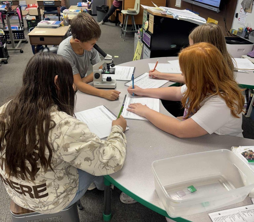 4 kids writing about what they saw in the microscope.