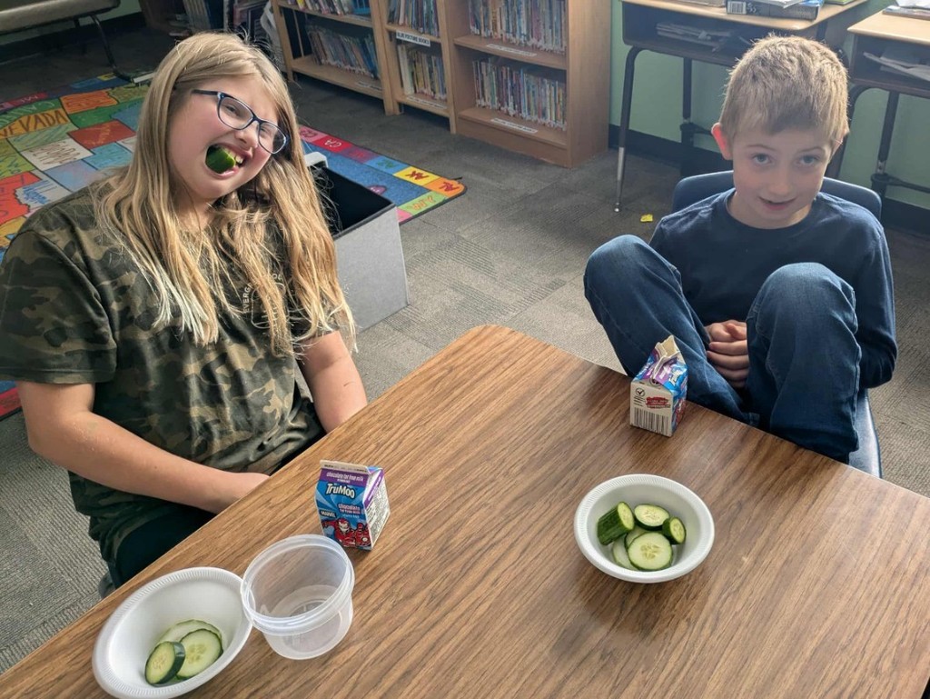 2 kids eating cucumbers.
