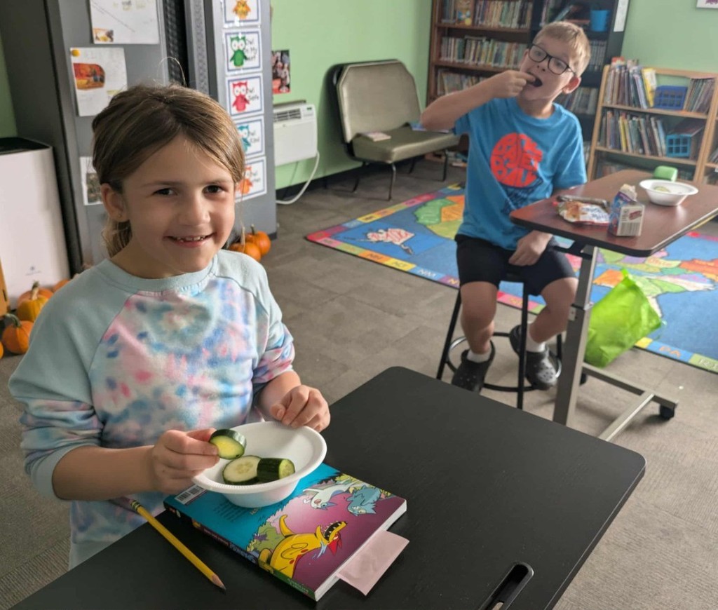 2 kids eating cucumbers