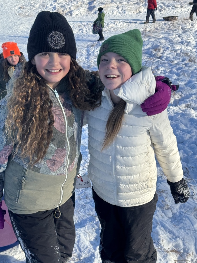 2 girls with their arms around each other on the hill.