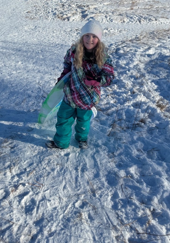 a girl climbing up the hill with a sled.