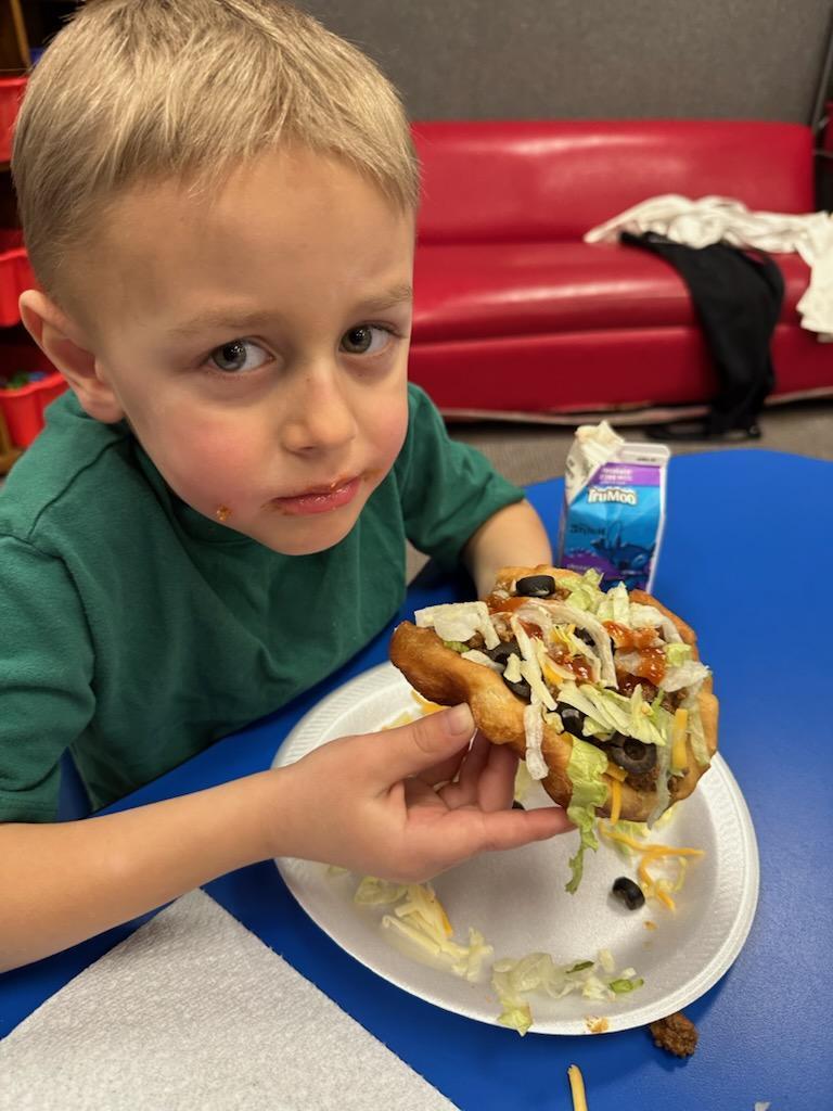 a boy eating fry bread tacos.