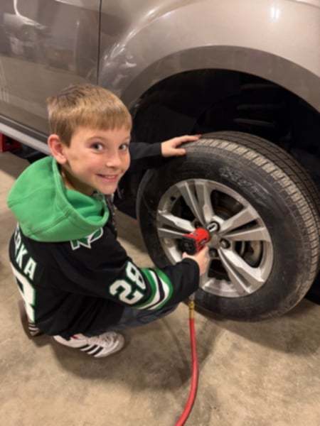 a boy using a lug nut drill