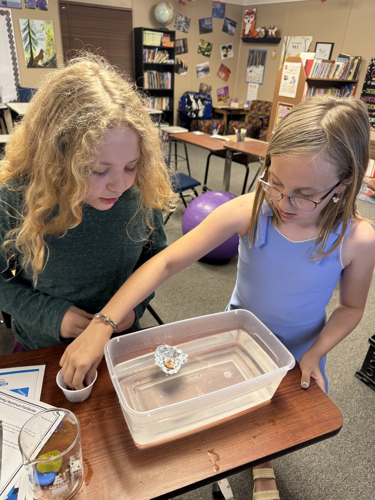 2 girls filling their foil boats with pennies