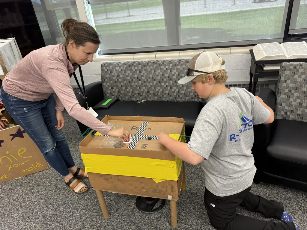 a kid and teacher playing air hockey