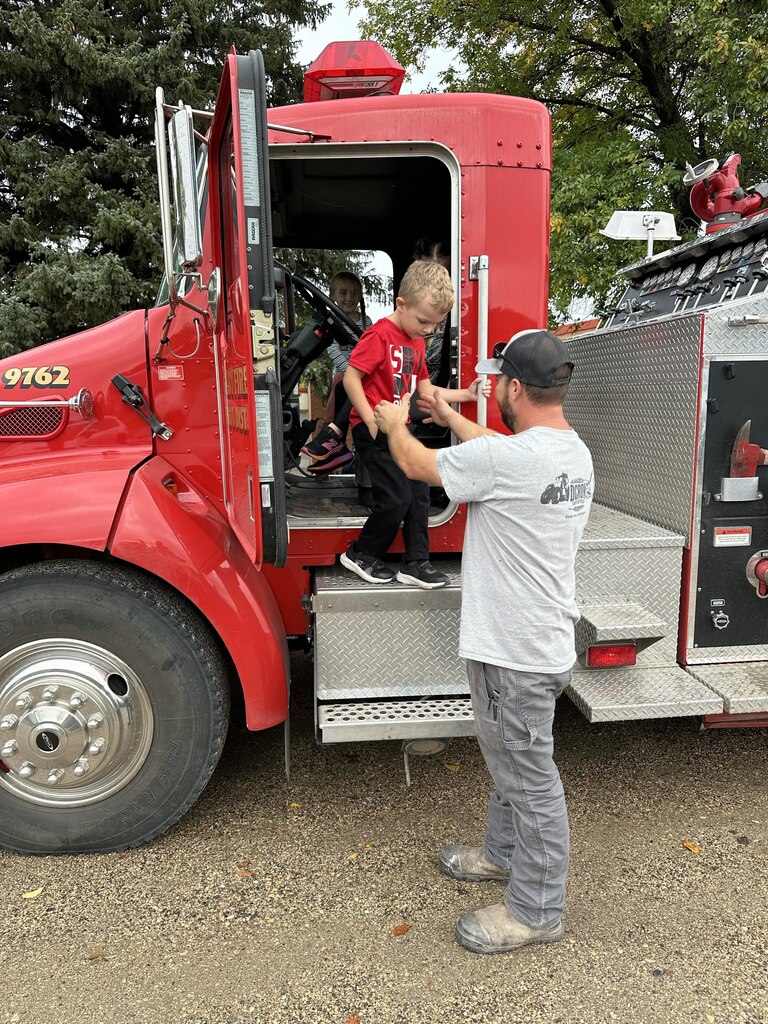 a firefighter helping a boy out of a truck