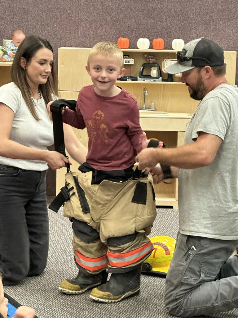 helping a boy get into the fireman's uniform