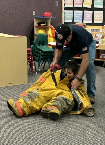 a fire fighter helping a boy get gear on
