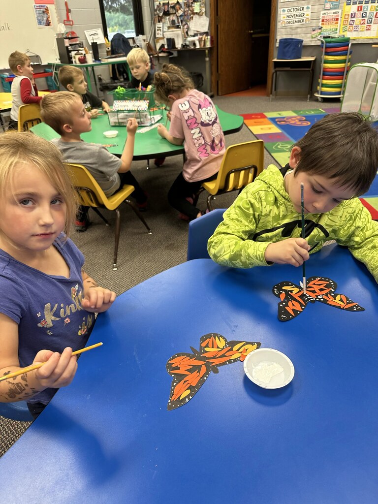2 kids painting their butterflies 