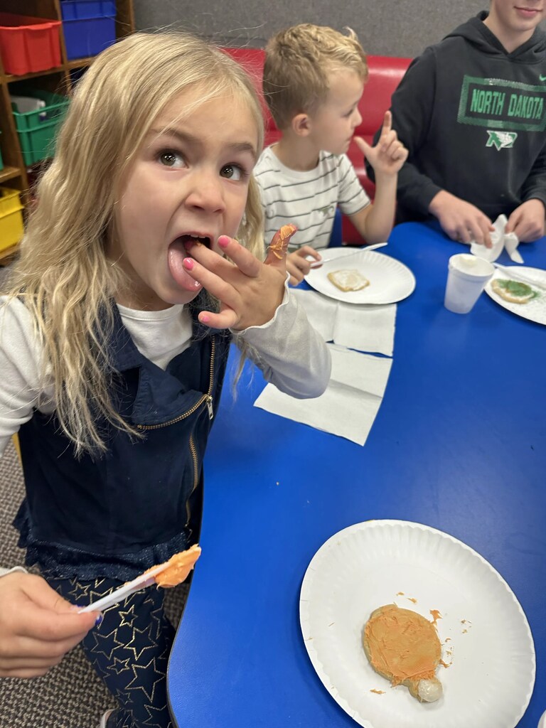 a girl licking the frosting off her finger 