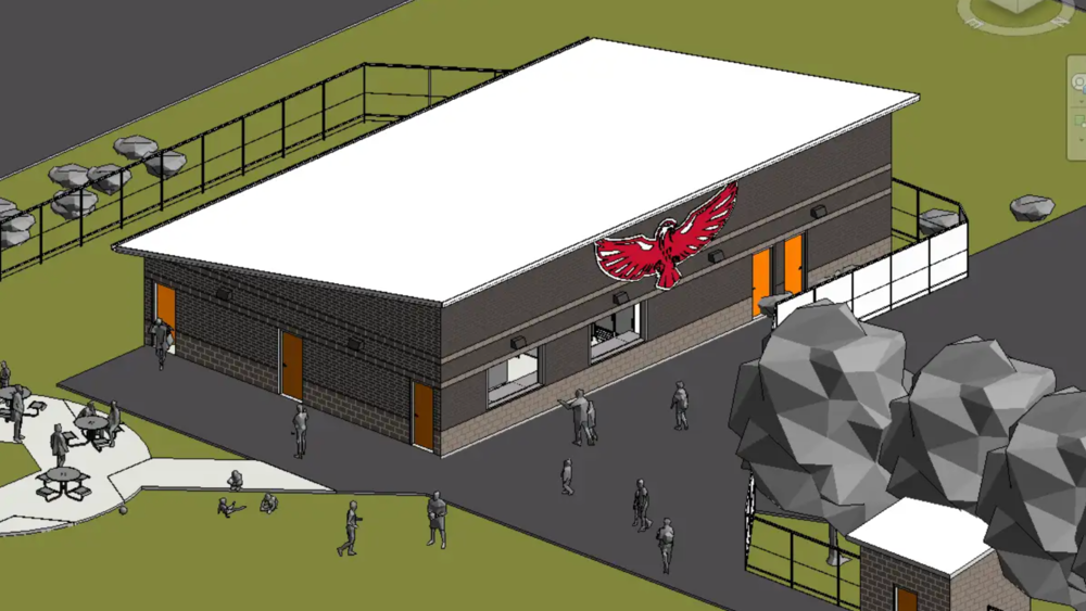 Architectural rendering of the proposed facility at the Charity Lucas Athletic Complex. The single-story brick building features a large white roof, concession service windows, multiple orange doors, and a red Eagle emblem on the exterior. Walkways, fencing, picnic tables, landscaping, and figures representing visitors surround the building.