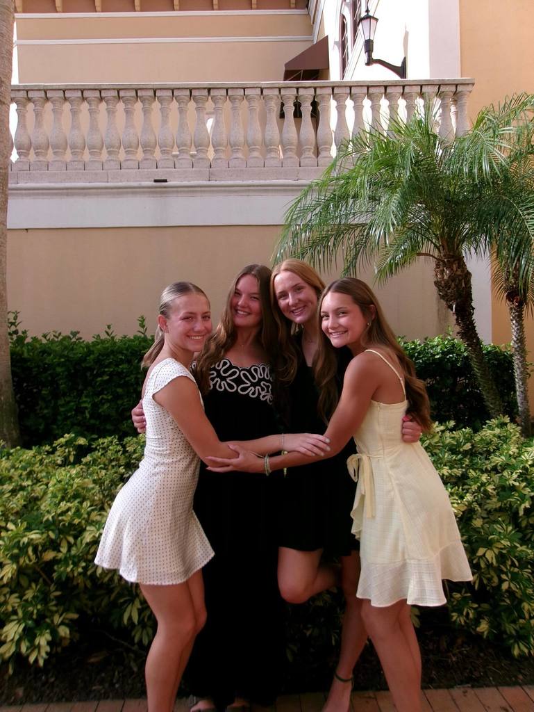 Group of 4 female students in dresses hugging