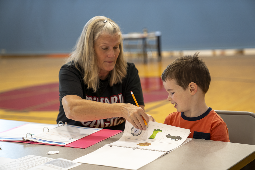 Boy smiling at paper with pictures on it