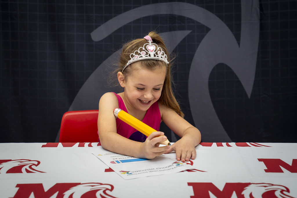 Girl Wearing a Tiara Signing a Paper