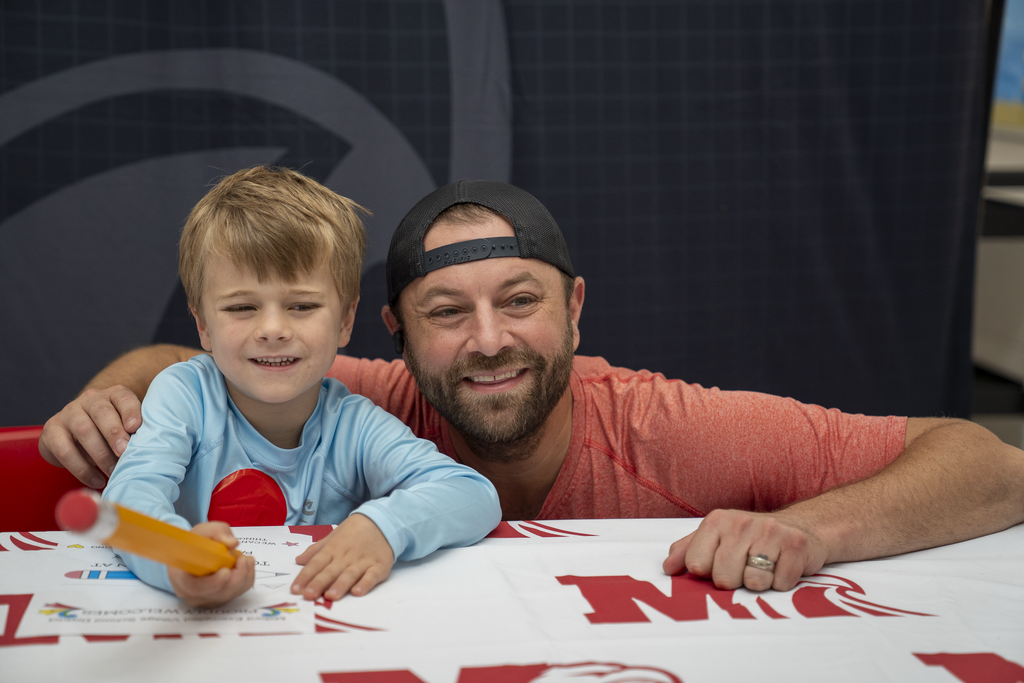 Man with backwards hat smiling with blonde-haired boy