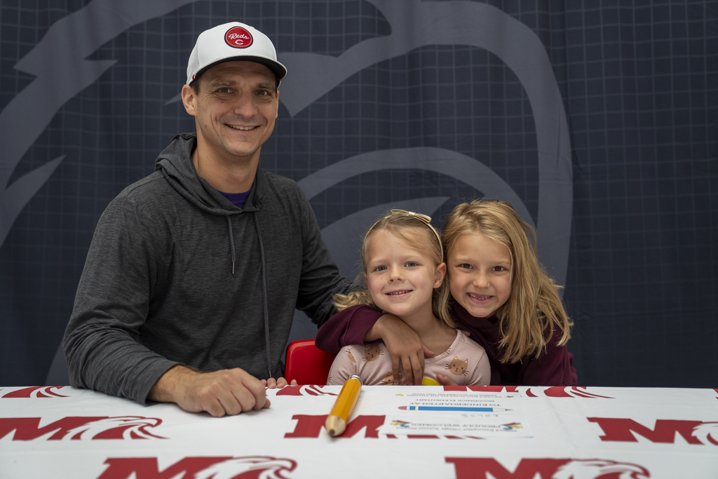 Man with hat next to family of two girls