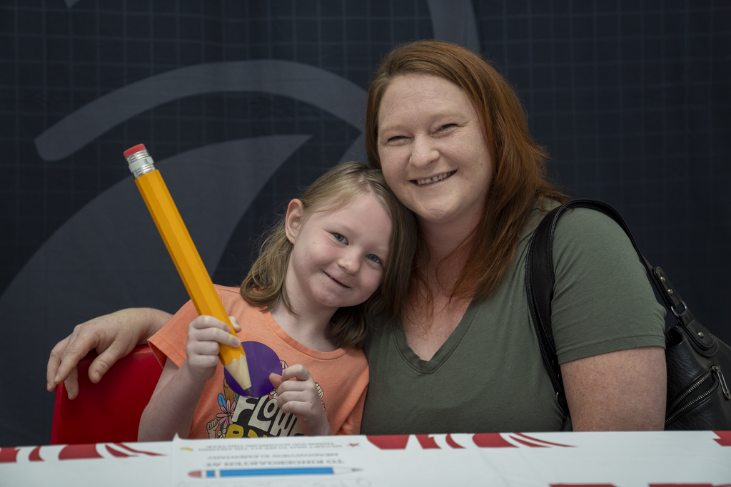 Daughter with a big pencil next to red-headed mom