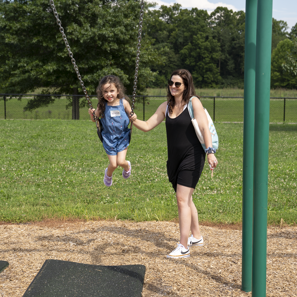 Woman pushing girl smiling on a swing