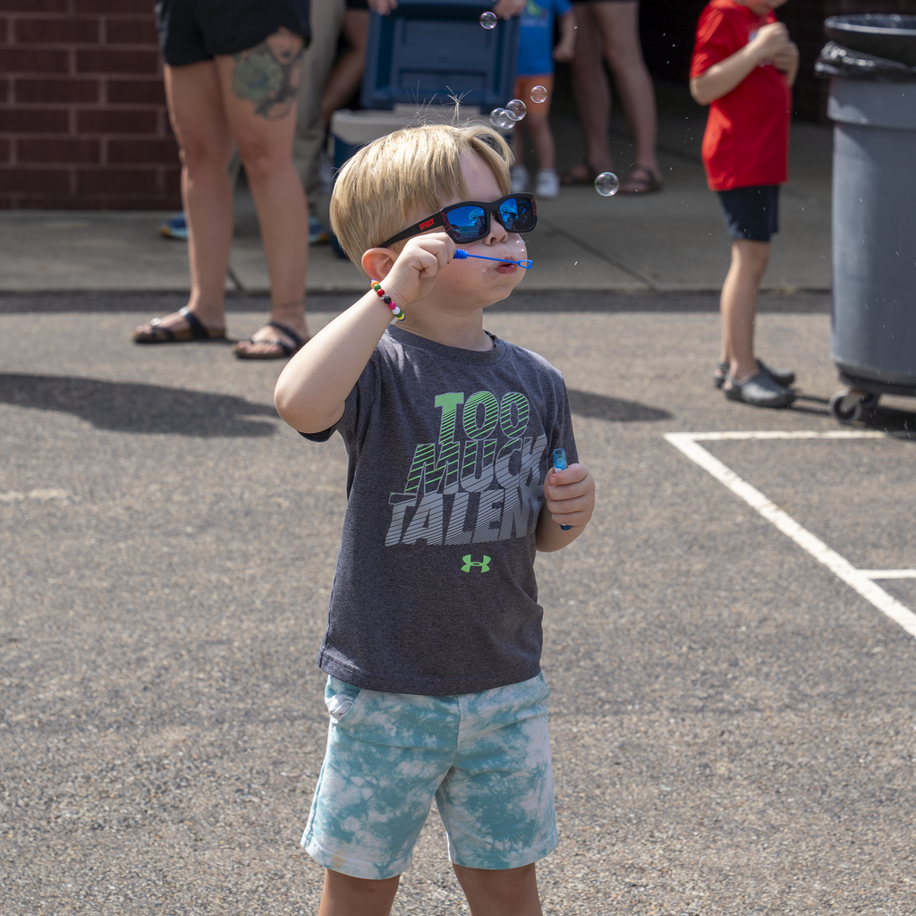 Boy with blonde hair blowing bubbles