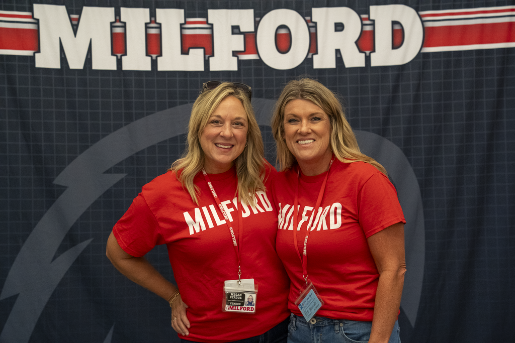 Two blonde women in front of a "Milford " backdrop
