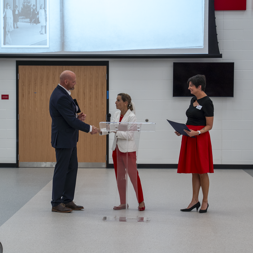 Woman at podium shaking superintendent's hand