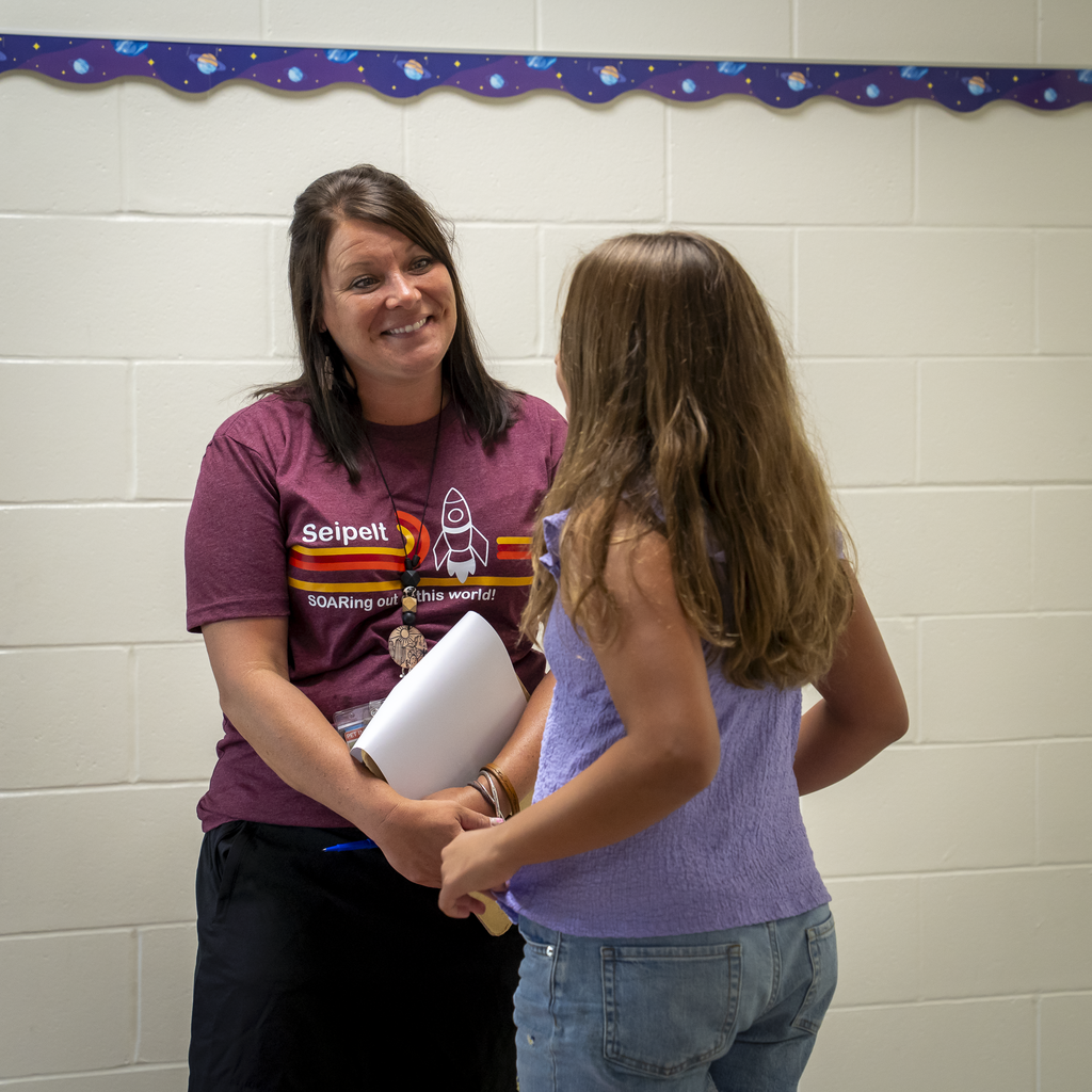 Student talking with smiling teacher