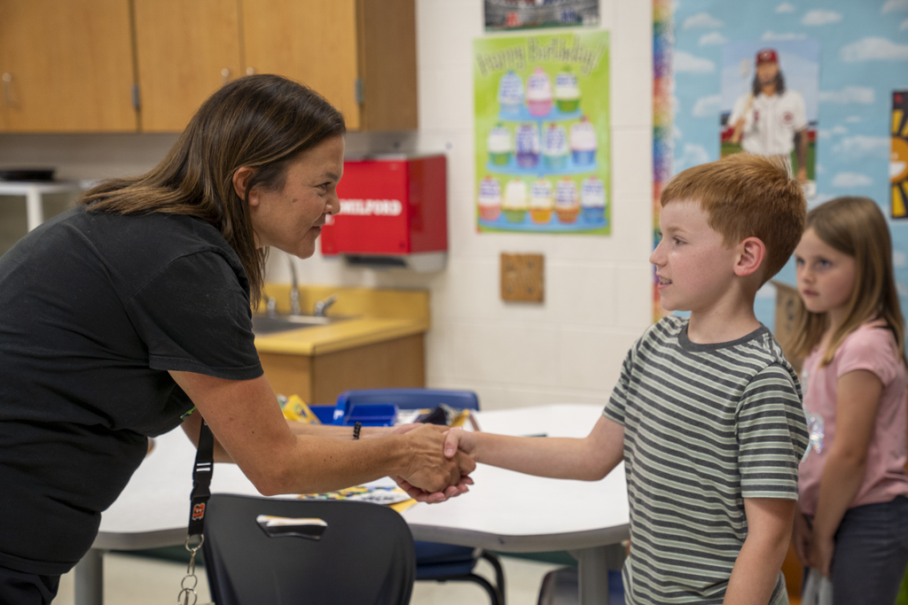 Teacher giving a red-haired boy a handshake