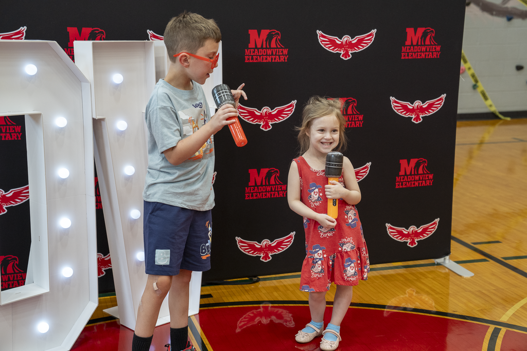 little girl with fake microphone next to a young boy with sunglasses and a fake microphone