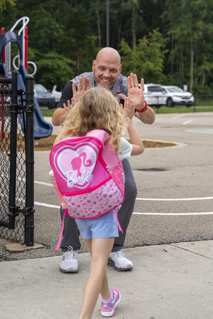 Bald man giving a double-high five to a girl with a barbie back-pack