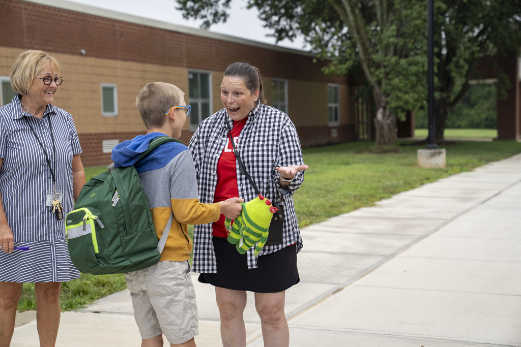 Teacher very excited to talk to student with green backpack