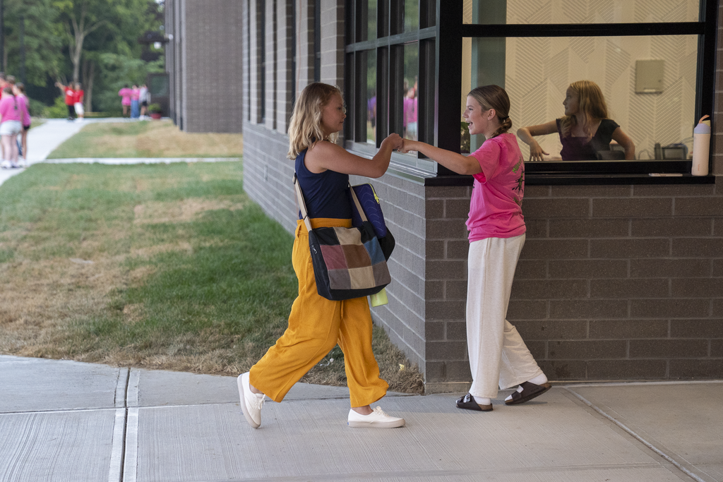 girl fist pumping another girl in yellow pants