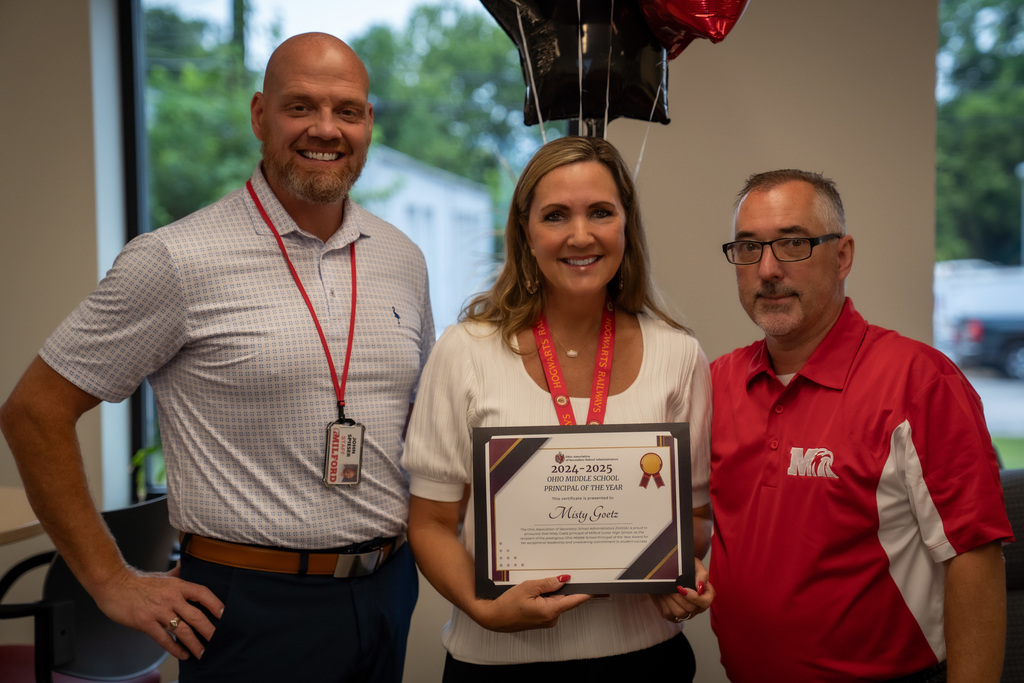 woman holding a certificate in-between two men.