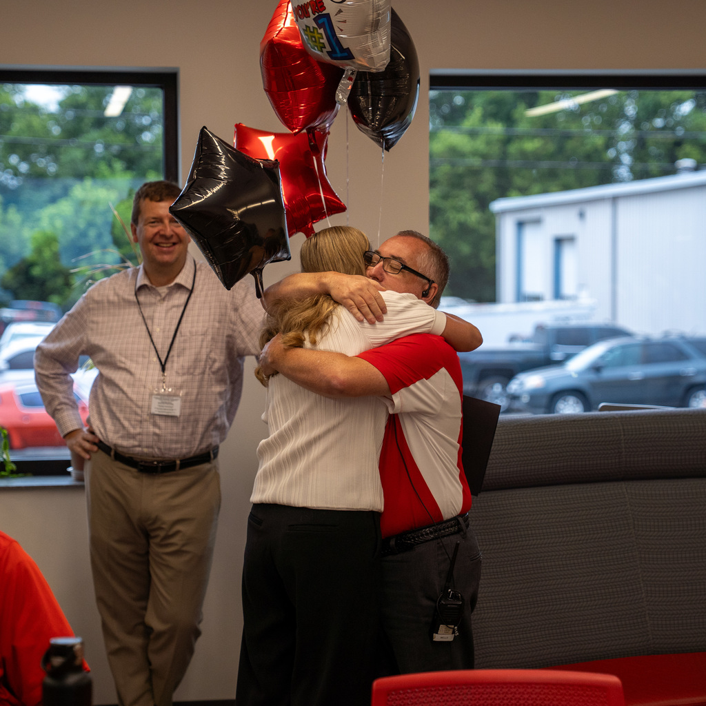 woman hugging man with glasses with balloons behind her