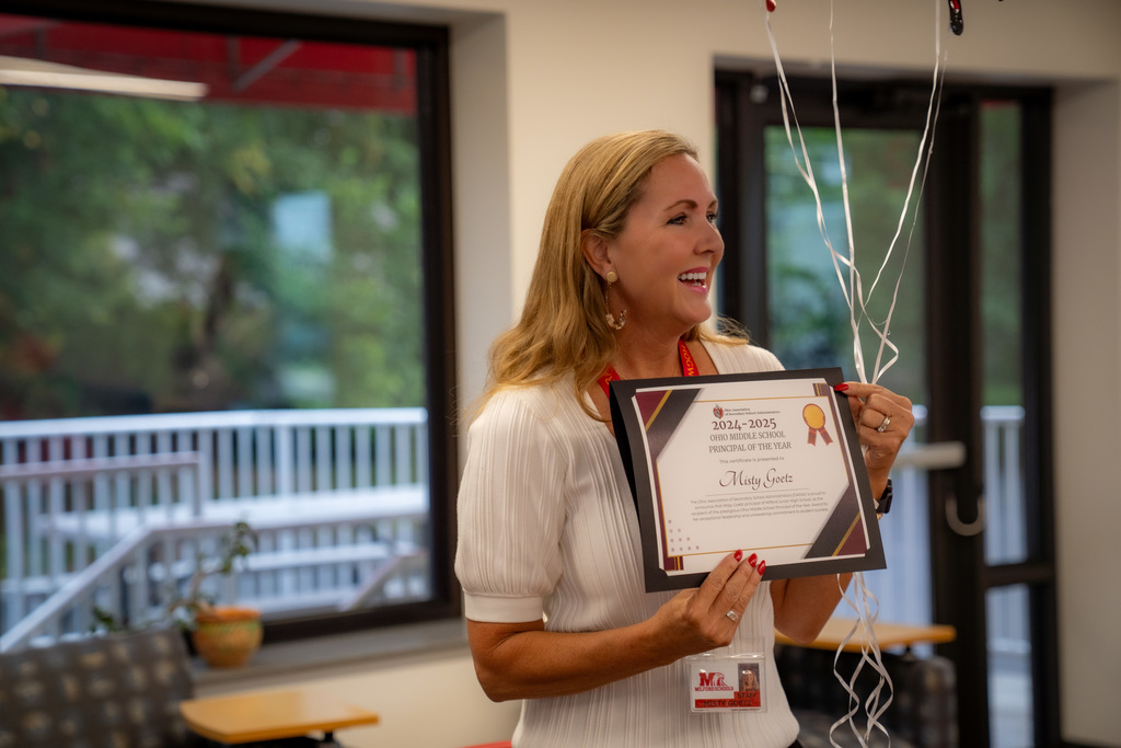 woman holding a certificate and balloon strings