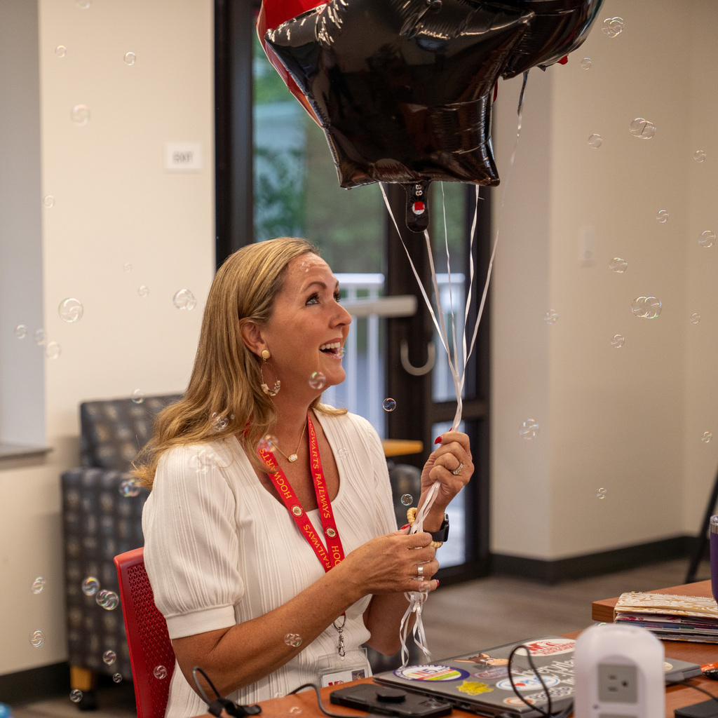 woman smiling looking up while holding balloons with bubbles around her