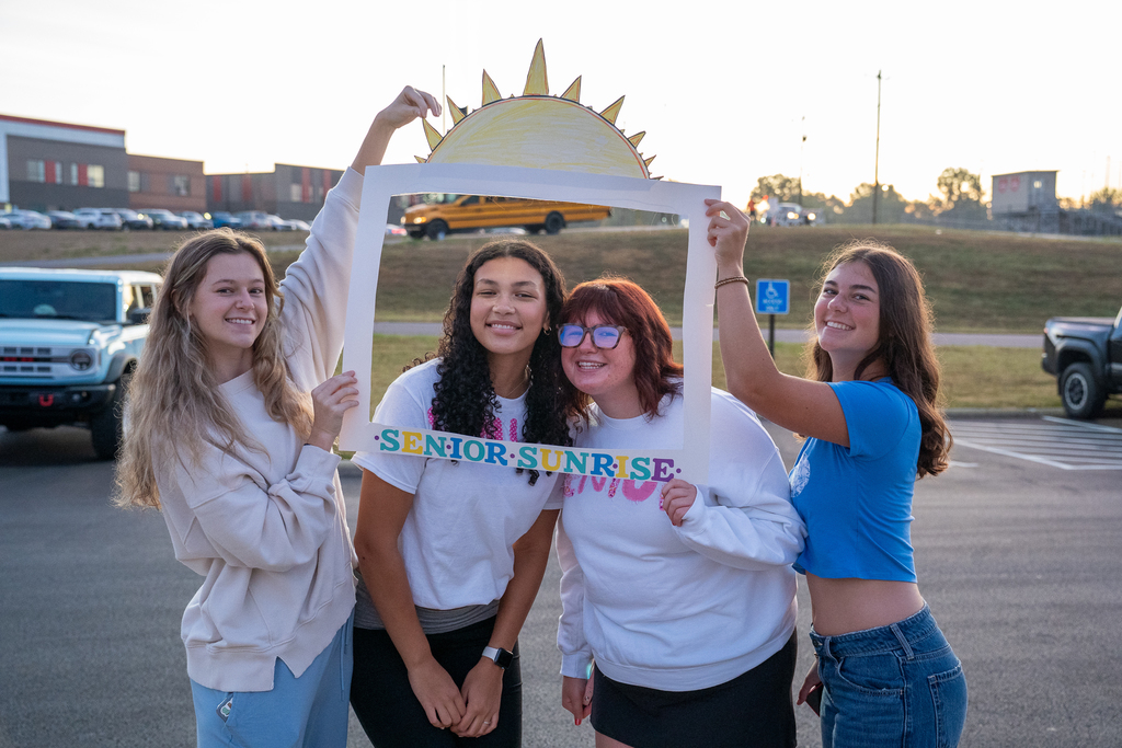 Group of 4 girls. Two of them are standing in a prop frame with a cutout sun