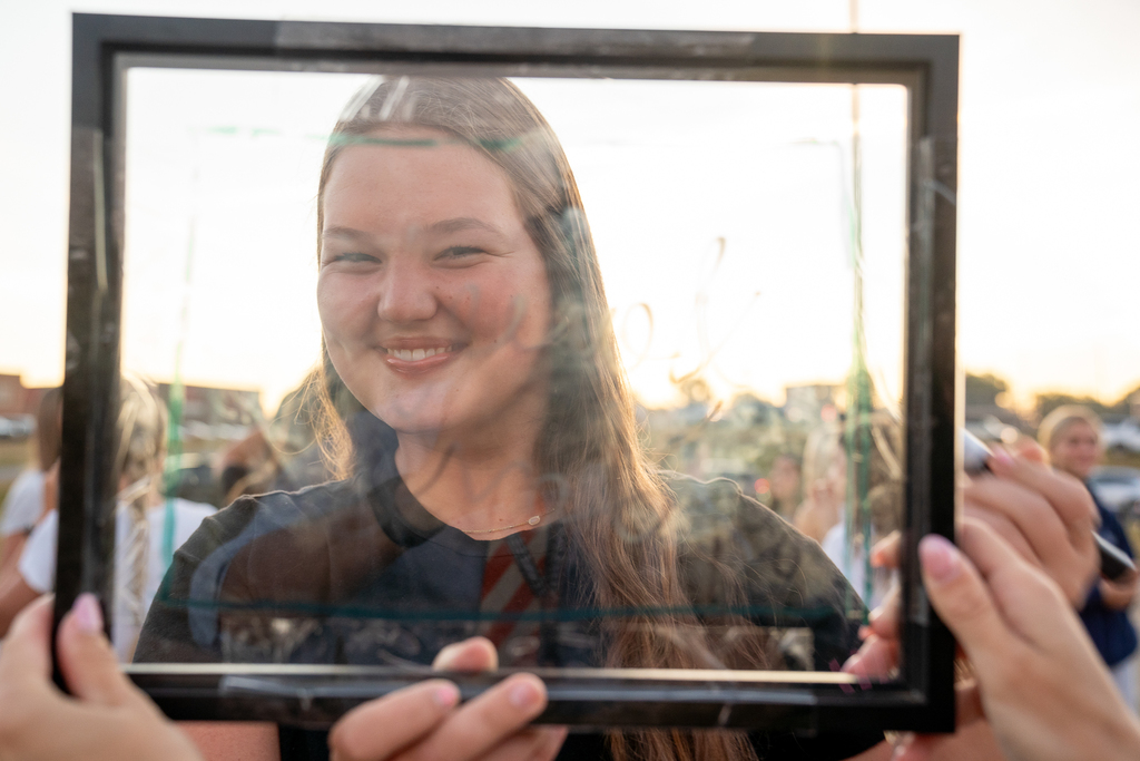 A girl smiling at the camera holding a frame