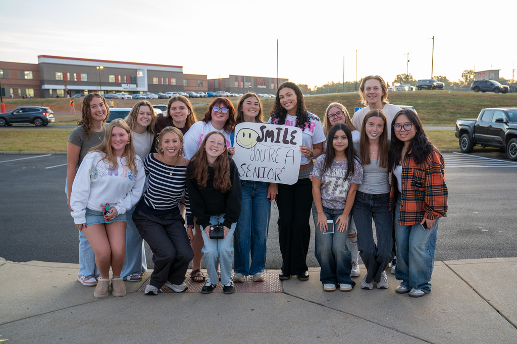 A group of teenageers holding a sign saying "Smile you're a senior"