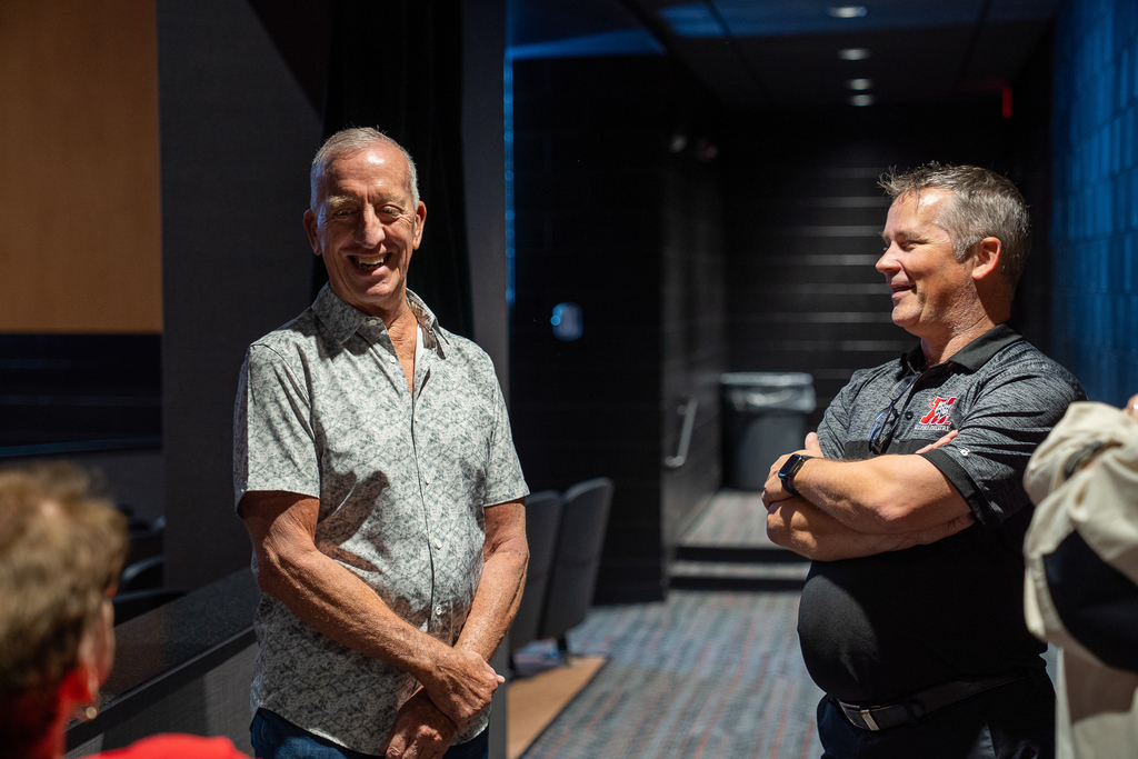 older man in a button down smiling while man next to him in a polo laughs