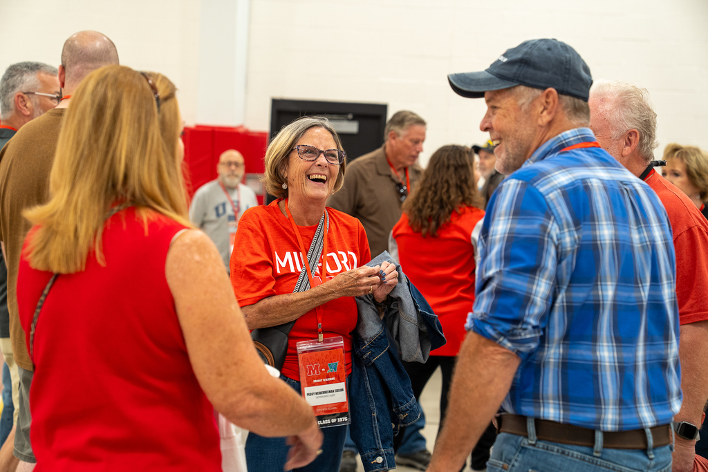 Woman in glasses wearing a red Milford Shirt laughing 