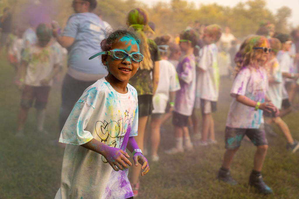A student with goggles on running with blue paint on their head